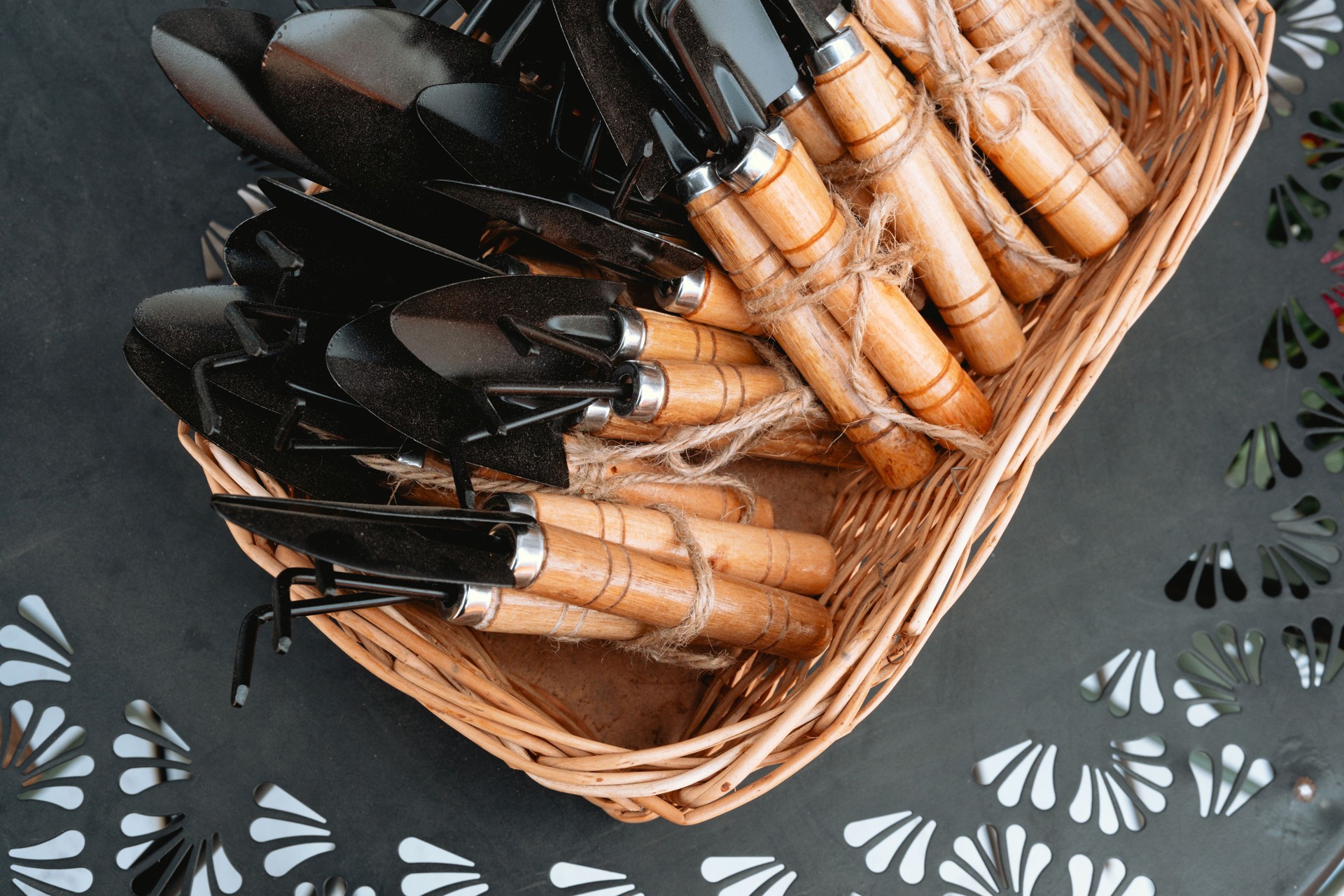 Garden tools arranged neatly in a woven basket on a dark surface